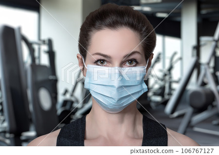 The coach is wearing a protective mask on the background of a gym. The coach is wearing a protective mask on the background of a gym. 106767127