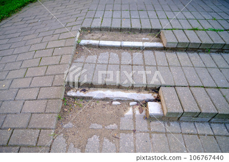 Damaged stair steps made from paving slab unsafe for pedestrians. Broken staircase. Broken stair with steps from gray paving slabs. Poor quality of brickwork. Renovation and repair work concept Damaged stair steps made from paving slab unsafe for pedestrians. Broken staircase. Broken stair with steps from gray paving slabs. Poor quality of brickwork. Renovation and repair work concept 106767440