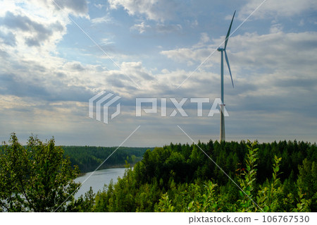 This is a former shale quarry with azure water and picturesque hills. Unlike the Narva shale settling ponds. A dark autumn day. Estonia, Aidu quarry. A tall wind turbine in the distance This is a former shale quarry with azure water and picturesque hills. Unlike the Narva shale settling ponds. A dark autumn day. Estonia, Aidu quarry. A tall wind turbine in the distance 106767530