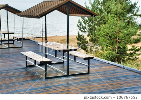 Relaxation area with tables by Lake Peipus. Lots of comfortable wooden sheds in a row with a view of the lake 106767552