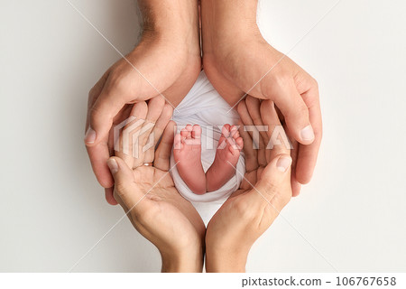 The palms of the father, the mother are holding the foot of the newborn baby on white background. Feet of the newborn on the palms of the parents. Photography of a child's toes, heels and feet 106767658