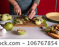 Woman cutting apples on a wooden cutting board for homemade traditional apple pie Woman cutting apples on a wooden cutting board for homemade traditional apple pie 106767854