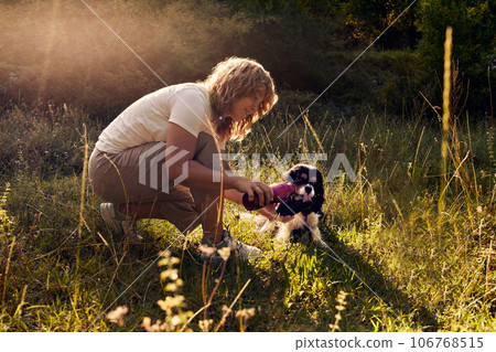 The girl pours water from a thermos for a dog on a walk. 106768515