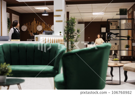 Concierge in managers office at resort, working on checking booking details and registration records for hotel bureaucracy. Young supervisor looking at files to enusre good staff service. 106768982