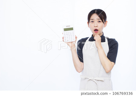 一位 30 多歲的家庭主婦在白色背景前拿著計算器，看起來很驚訝 106769336