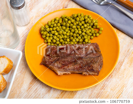 Grilled veal steak with vegetable garnish of canned green peas. Healthy dinner concept 106770759