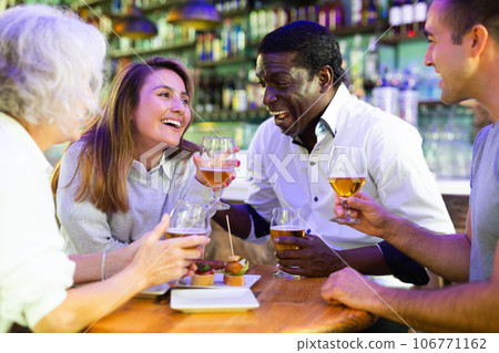 Group of friends drinking beer in bar and celebrating holidays. Focus on young woman 106771162