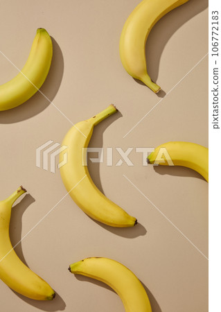 Against the beige background, few fresh bananas are displayed. Concept of organic fruit. Banana (Musaceae) is also rich in vitamin B6, which improves cognitive function Against the beige background, few fresh bananas are displayed. Concept of organic fruit. Banana (Musaceae) is also rich in vitamin B6, which improves cognitive function 106772183