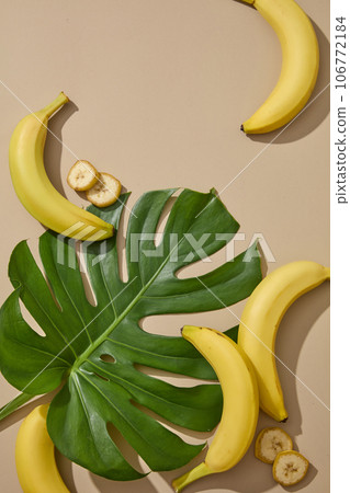 A tropical green leaf displayed with some bananas on beige background. Eating bananas regularly can improve nerve and brain function A tropical green leaf displayed with some bananas on beige background. Eating bananas regularly can improve nerve and brain function 106772184