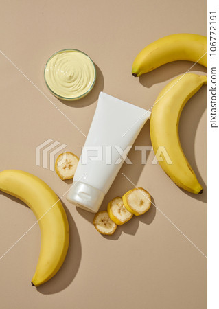 White tube with empty label arranged with a petri dish of skin care cream. Banana (Musaceae) contains anti-aging benefits that can have mild exfoliating properties White tube with empty label arranged with a petri dish of skin care cream. Banana (Musaceae) contains anti-aging benefits that can have mild exfoliating properties 106772191