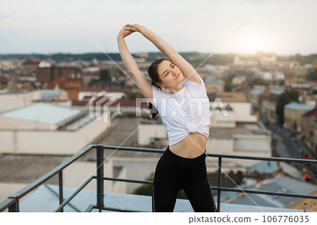 Young person raising hands in stretches on city background 106776035
