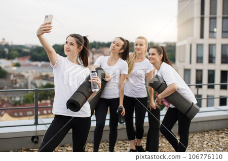 Yoginis taking self-photo on mobile after outdoor exercises Yoginis taking self-photo on mobile after outdoor exercises 106776110