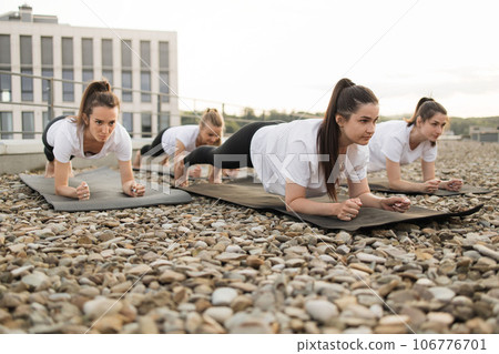 Women doing forearm plank on yoga mats in open air on roof Women doing forearm plank on yoga mats in open air on roof 106776701