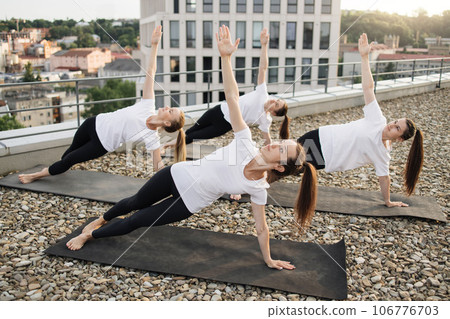 Yoga enthusiasts achieving Side Plank Pose in outdoor class Yoga enthusiasts achieving Side Plank Pose in outdoor class 106776703