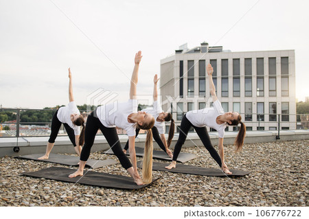 Ladies extending body while looking up in sky on terrace 106776722