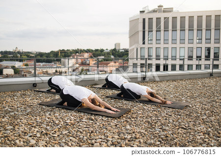 Yoginis meditating in open air when sitting on knees on mats 106776815