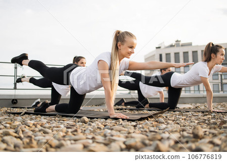 Yoga enthusiasts practicing balance pose on roof terrace Yoga enthusiasts practicing balance pose on roof terrace 106776819