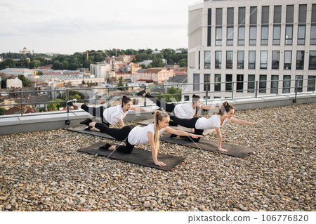 Four ladies stretching arms and legs while kneeling on mats Four ladies stretching arms and legs while kneeling on mats 106776820