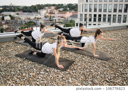 Females balancing in kneeling yoga pose on mats outdoors 106776823