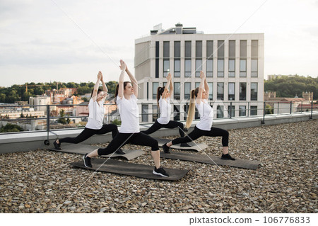 Women working out standing asana on mats on gravel terrain 106776833