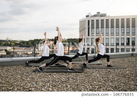Women working out standing asana on mats on gravel terrain 106776835