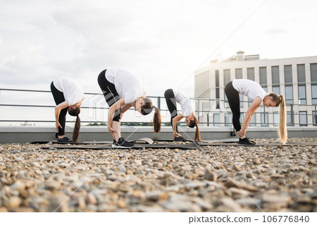 Ladies in activewear bending forward during outdoor exercise Ladies in activewear bending forward during outdoor exercise 106776840