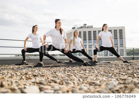 Slim females elongating muscles in outdoor workout session Slim females elongating muscles in outdoor workout session 106776849