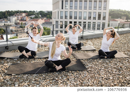 Yoginis creating self-portrait on phone in class on terrace 106776936