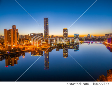 Yekaterinburg city and pond aerial panoramic view at summer or early autumn night. Night city in the early autumn or summer. Yekaterinburg city and pond aerial panoramic view at summer or early autumn night. Night city in the early autumn or summer. 106777163