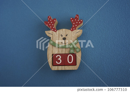 Festive wooden deer Viva Magenta cubes 30 blue background close-up top view. Christmas concept date or time Festive wooden deer Viva Magenta cubes 30 blue background close-up top view. Christmas concept date or time 106777310