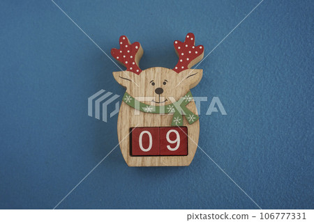 Festive wooden deer Viva Magenta cubes 09 blue background close-up top view. Christmas concept date or time 106777331
