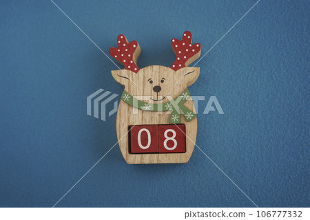 Festive wooden deer with Viva Magenta cubes 08 on blue background close-up top view. Christmas concept of date or time Festive wooden deer with Viva Magenta cubes 08 on blue background close-up top view. Christmas concept of date or time 106777332