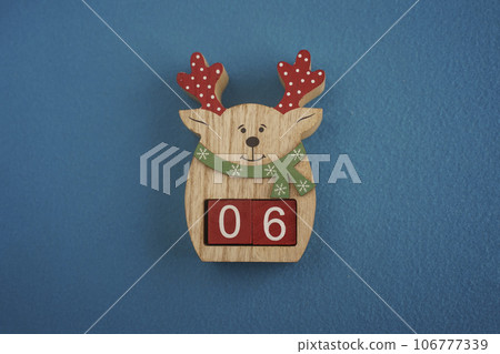 Festive wooden deer with Viva Magenta cubes 06 on blue background close-up top view. Christmas concept of date or time Festive wooden deer with Viva Magenta cubes 06 on blue background close-up top view. Christmas concept of date or time 106777339