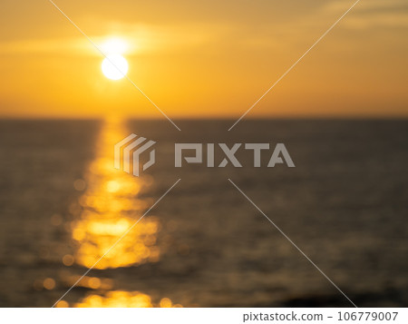 Blurry photo. The calm sea surface sparkles reflecting the sunset sky and the setting sun. Blurry photo. The calm sea surface sparkles reflecting the sunset sky and the setting sun. 106779007