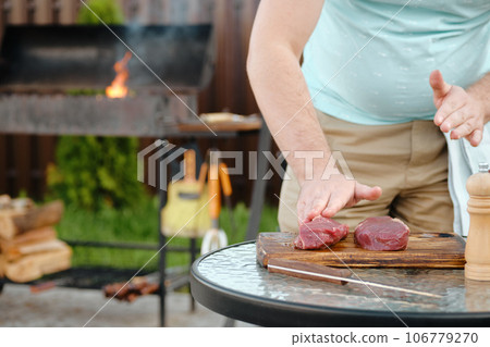 Unrecognizable man spreading olive oil over raw beef steak Unrecognizable man spreading olive oil over raw beef steak 106779270