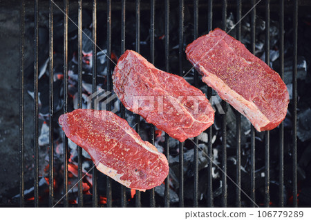 Top view of beef steaks on grid of grill 106779289