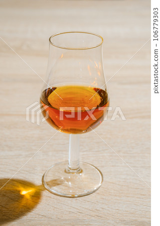 Tulip glass with cognac on wooden table Tulip glass with cognac on wooden table 106779303