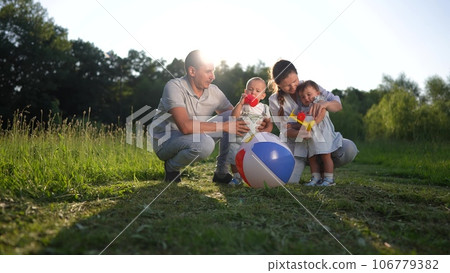 family playing with two babies in the park in nature. happy family kid dream concept. parents play ball and toys with little baby toddlers in the park. happy family relaxing in summer lifestyle family playing with two babies in the park in nature. happy family kid dream concept. parents play ball and toys with little baby toddlers in the park. happy family relaxing in summer lifestyle 106779382
