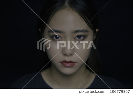 portrait of young woman on black background 106779807