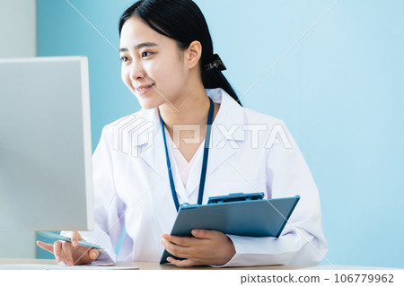 A woman in a white coat working on a computer A woman in a white coat working on a computer 106779962