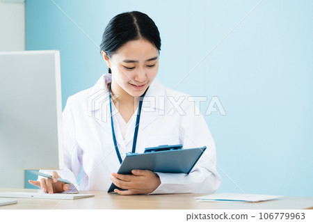 A woman in a white coat working on a computer A woman in a white coat working on a computer 106779963
