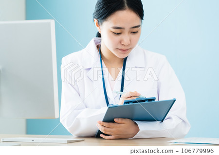 A woman in a white coat working on a computer A woman in a white coat working on a computer 106779996