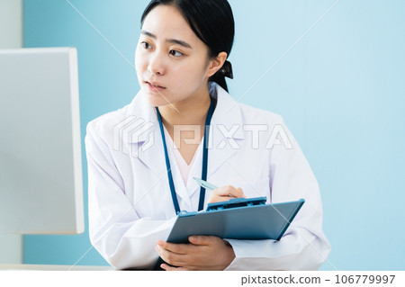 A woman in a white coat working on a computer 106779997
