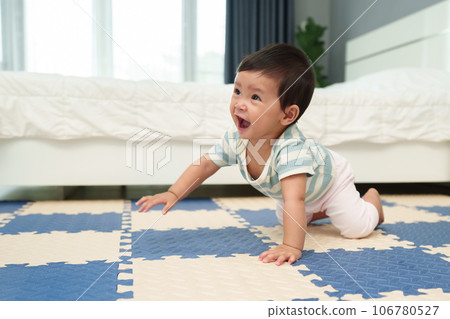 happy infant baby crawling on play mat or jigsaw floor in bedroom 106780527