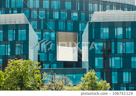Modern glass commercial exterior of office building architecture. Window covered abstract building with green trees in front. Contemporary high rise structures 106781129