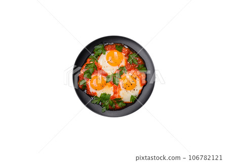 Shakshuka, a dish with fried eggs with tomato sauce, sweet pepper, garlic, onions, spices and herbs 106782121