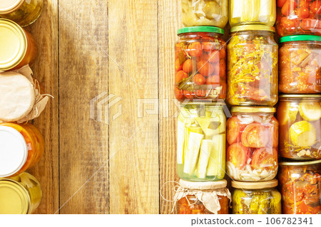 Healthy homemade fermented food. Various types of canned vegetables in glass jars on a rustic table. Home economics, autumn harvest preservation. View from above. Copy space. 106782341