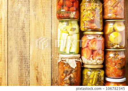 Healthy homemade fermented food. Various types of canned vegetables in glass jars on a rustic table. Home economics, autumn harvest preservation. View from above. Copy space. 106782345