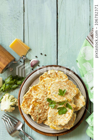 Fried vegetarian cutlets or pancakes. Cauliflower vegetable fritters with cheese on a rustic kitchen table. View from above. Copy space. 106782371