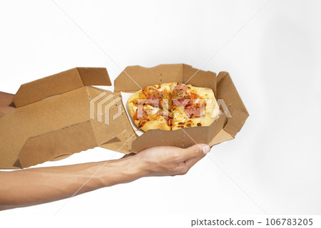 A human hand holding pizza on a cardboard box A human hand holding pizza on a cardboard box 106783205